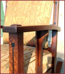 Close-up view of the arm which arches upward and outward supported midway by a single slat with a long corbel.  The front leg with the Ebony inlay pierces the top of the arm with it's pinned through-tenon construction.